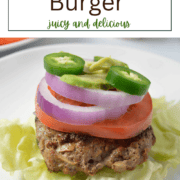 A juicy, seared ranch burger patty served on a plate with fresh lettuce, tomato, and avocado slices.