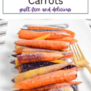 Tender, herb-flecked orange carrot sticks roasted to a golden brown, served on a white rectangular plate with a garnish of fresh rosemary.