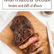 Slices of juicy, grilled balsamic marinated flank steak on a wooden cutting board, showing a perfect medium sear.