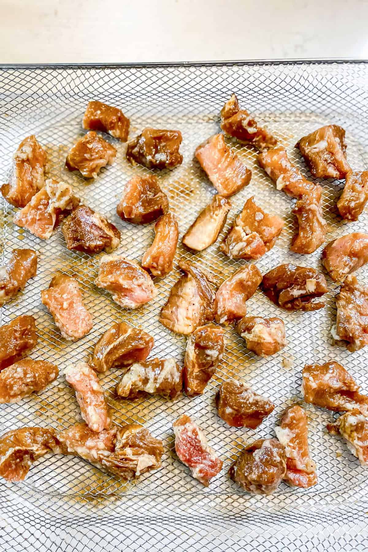 Prok Bites in marinade laid out on air fyrer pan make pork bites. www.atwistedplate.com/pork-bites