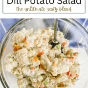 A glass bowl filled with cubed potatoes, bright red, orange, and yellow roasted bell peppers, and fresh green dill in a creamy dressing.