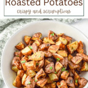A baking sheet filled with golden-brown, crispy cubed potatoes seasoned with herbs and garlic.