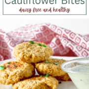 Golden-brown roasted cauliflower bites served on a white plate with a side of creamy dipping sauce.