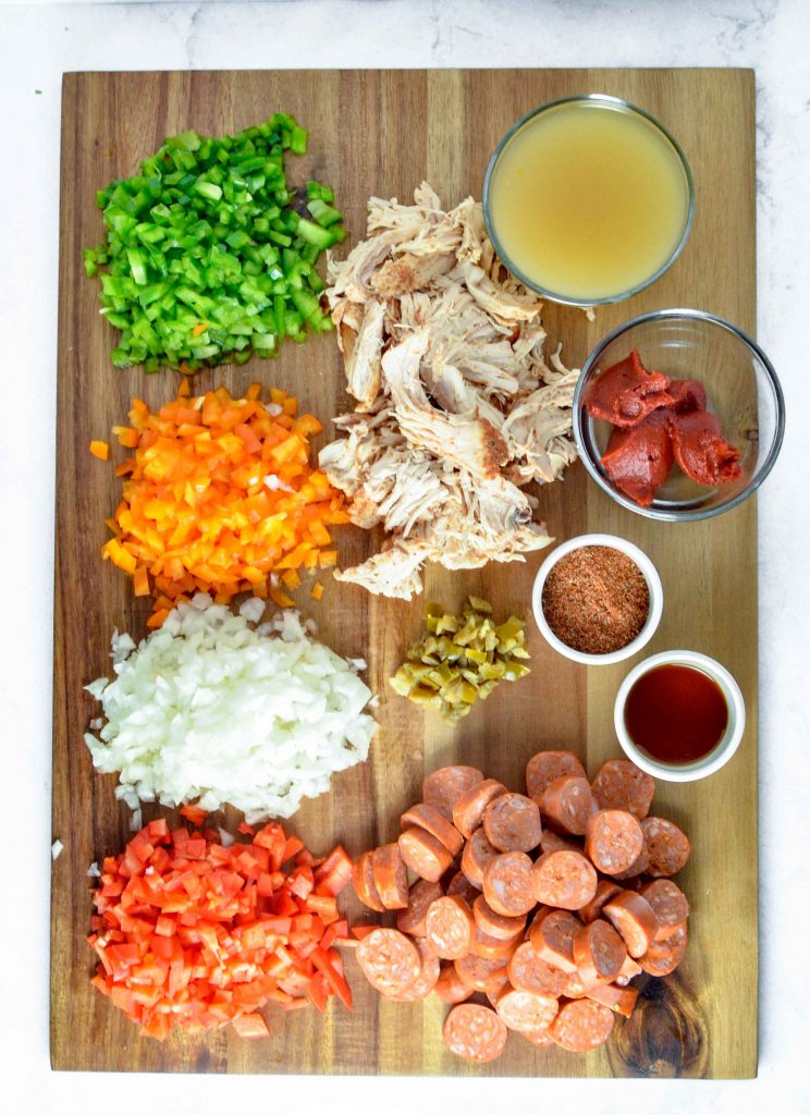 Ingredients for Cajan Chicken, Sausage and Peppers on a wood cutting board. www.atwistedplate.com