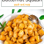 Cubed butternut squash roasted to a golden brown on a baking sheet, seasoned with minced garlic and dried sage.
