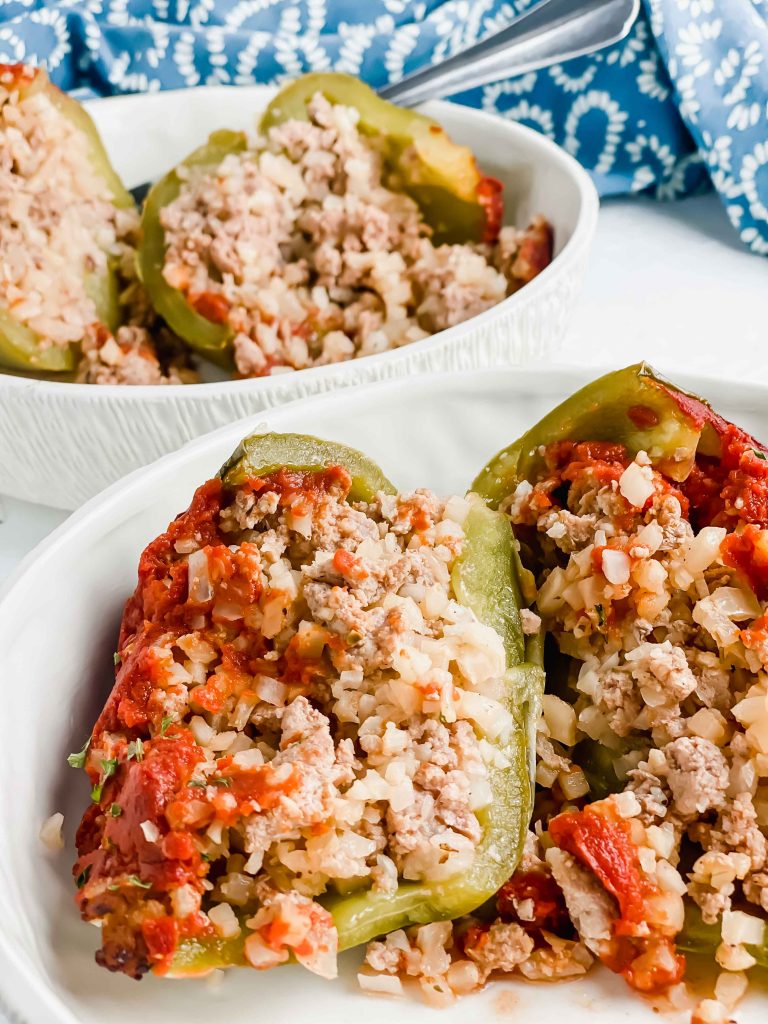 Image for Pork & Cauliflower Rice Stuffed Peppers of a cut open stuffed pepper in a white bowl. https://www.atwistedplate.com/pork-cauliflower-rice-stuffed-pepper/
